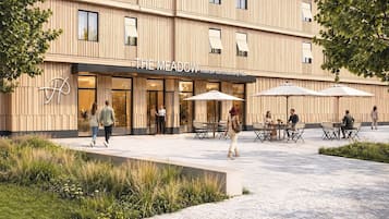 Een hotel met een moderne gevel, een terras en een logo op de muur.