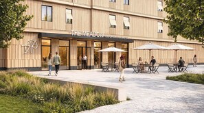 A hotel with a modern facade, outdoor seating area, and a logo on the wall.