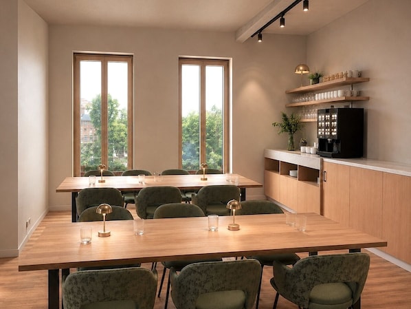 A modern dining area with a wooden table and chairs, large windows, and a kitchen area with shelves and appliances.