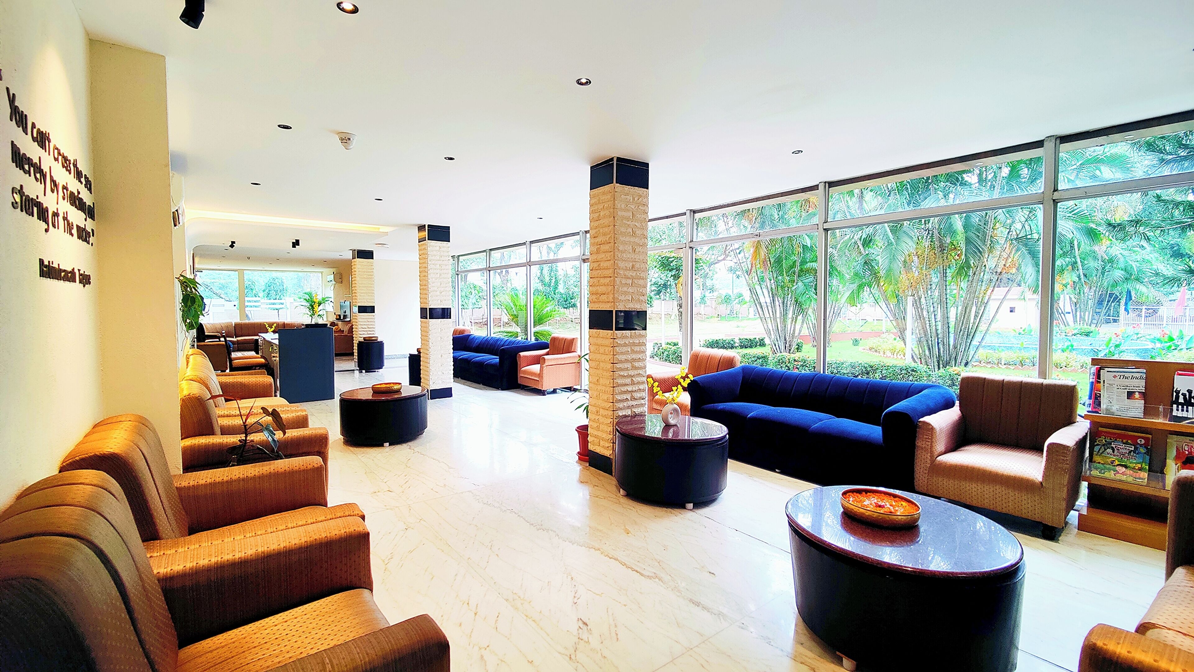 A spacious lobby with seating areas, large windows, and a view of greenery outside.