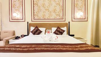 A hotel room with a bed, a chair, a bedside table, and wall-mounted lights.
