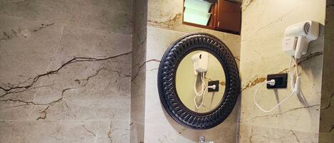 A bathroom with a marble wall, a sink, a toilet, and a mirror.