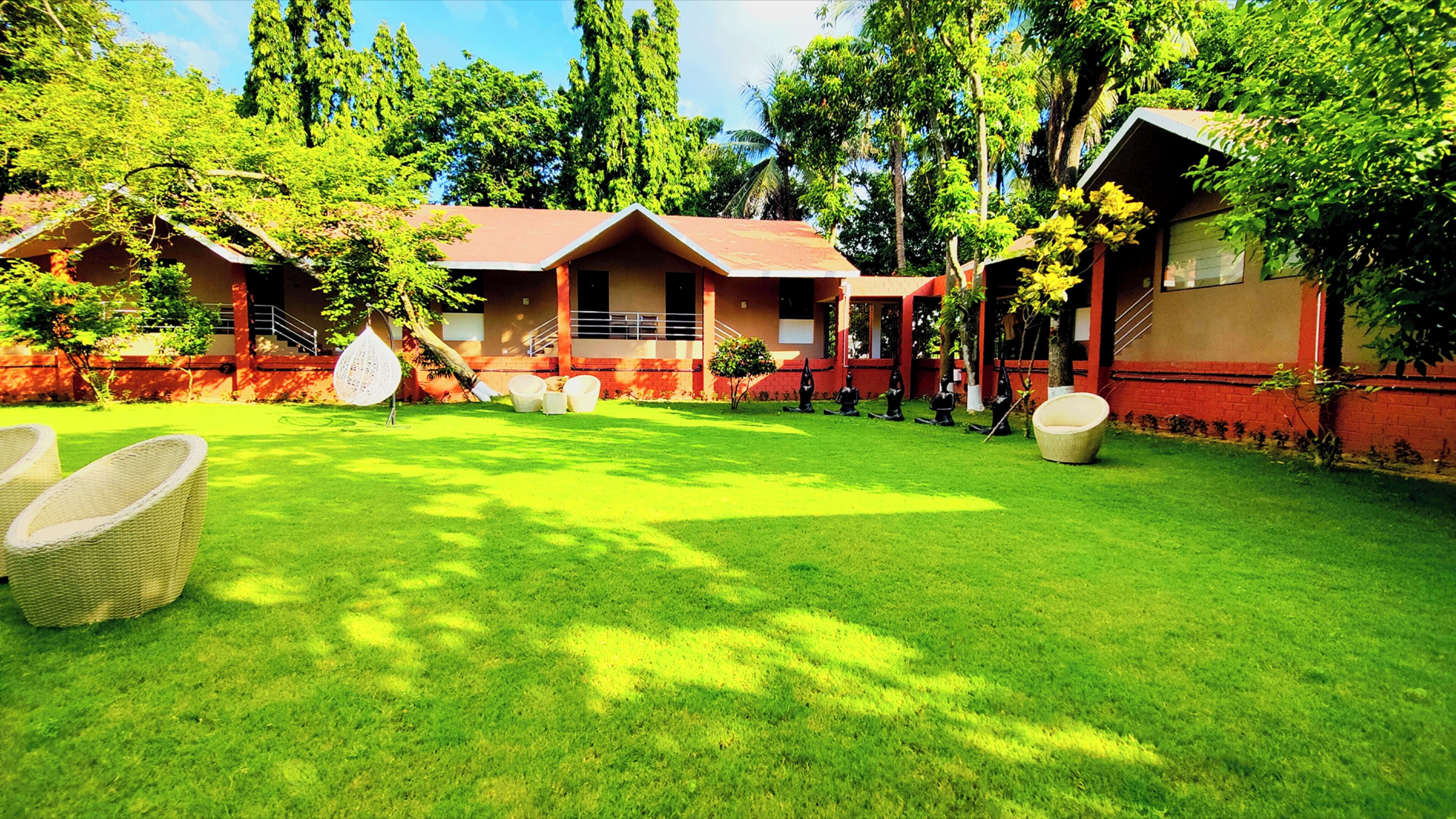A courtyard with a lawn, outdoor seating, and a building with a red facade.