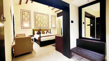 A hotel room with a bed, a chair, a large mirror, and a door.
