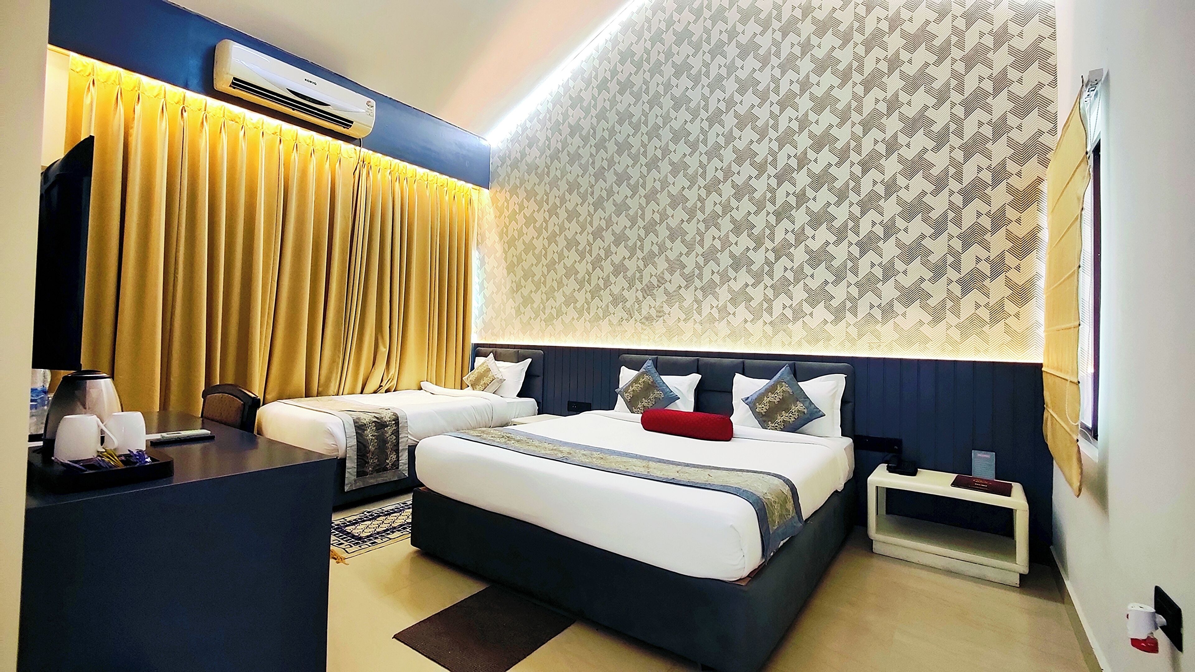 A hotel room with a large bed, a desk with a coffee maker, and a patterned wall.