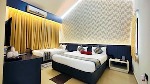 A hotel room with a large bed, a desk with a coffee maker, and a patterned wall. - Mark & Meadows (Bolpur)