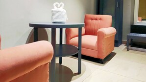 Una habitación con una mesa redonda, un sillón capitoné y un sofá.