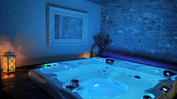 A hot tub with multiple jets, a framed picture on the wall, a stone wall, and a lantern on the floor.