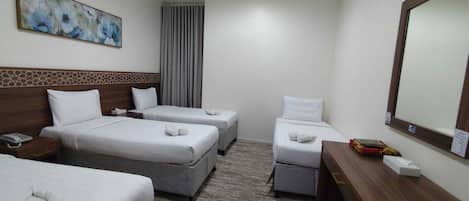 A hotel room with two beds, a desk, a mirror, and a painting on the wall.