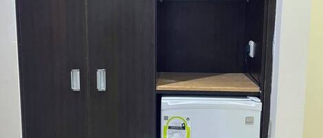A wardrobe with a built-in mini-fridge and a shelf.