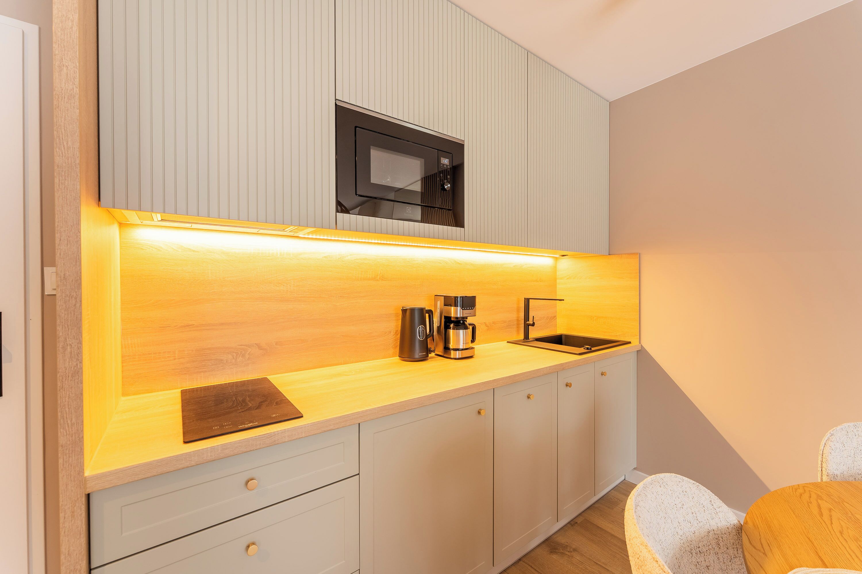 A modern kitchen with a microwave, coffee maker, and wooden countertop.