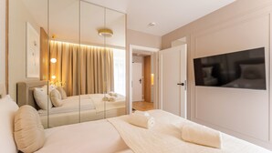 A hotel room with a bed, a large mirror, a television, and a door leading to another room. - Posesja Plażowa 4c II & SPA (Grzybowo)