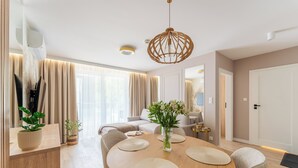A modern dining area with a round wooden table, cushioned chairs, and a hanging light fixture. - Posesja Plażowa 4c II & SPA (Grzybowo)
