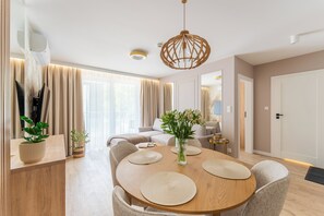 Ein stilvoller Essbereich mit einem runden Holztisch, gepolsterten Stühlen und einer hängenden Leuchte.
