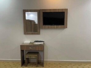 A room with a wooden desk, a mirror, and a mounted television. - Al Abrag Hafawa Hotel (Makkah)