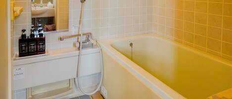 A bathroom with a bathtub, a shower, and a sink with toiletries.