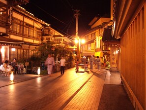A traditional Japanese street at night with people walking and traditional buildings. - Shibuonsen YAMAICHIYA (Yamanouchi)