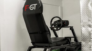 Un siège de course noir orné du logo « F-GT », un volant et une structure en métal.
