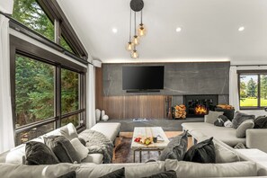 Una sala de estar moderna con chimenea, ventanas amplias y un televisor de pantalla plana.