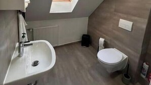 Ein kleines Badezimmer mit Dachfenster, Waschbecken und Toilette.