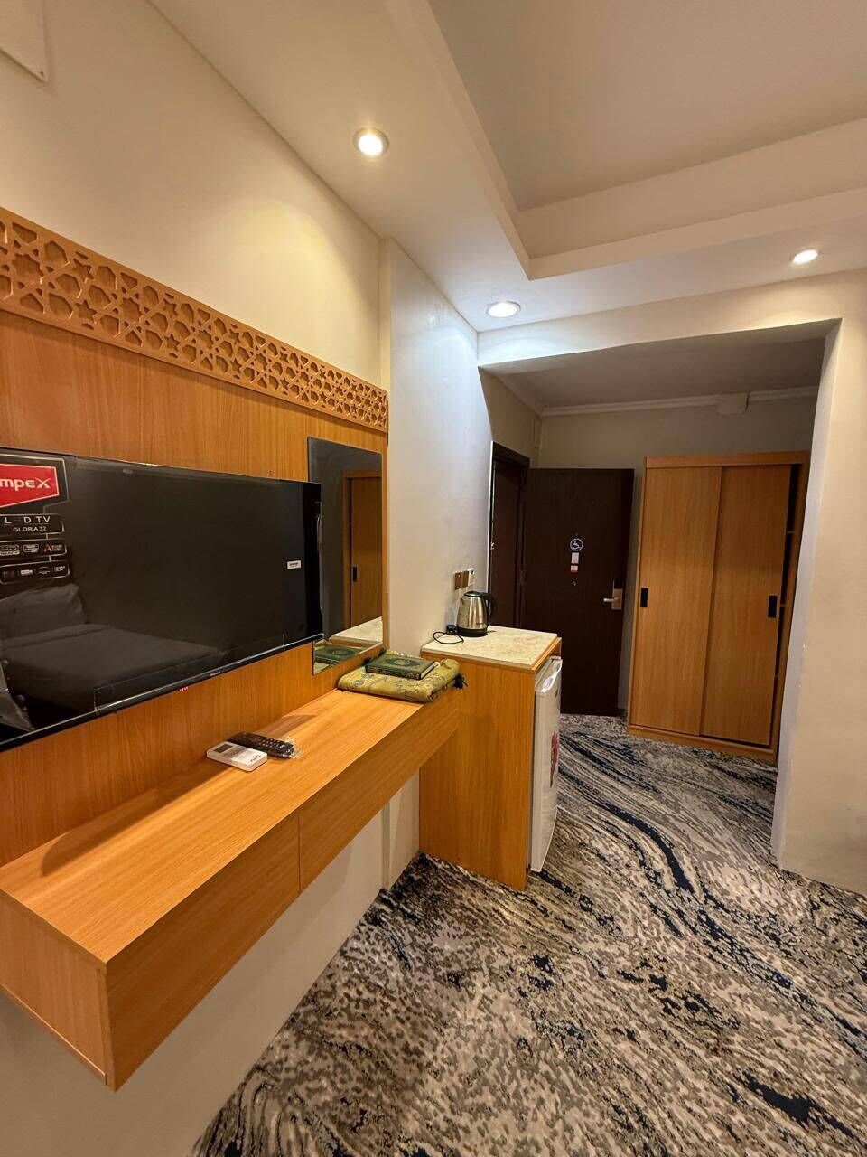 Une chambre d’hôtel équipée d’une télévision à écran plat, d’un bureau en bois et d’un mini-bar.