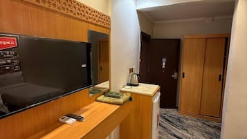Une chambre d’hôtel équipée d’une télévision à écran plat, d’un bureau en bois et d’un mini-bar.