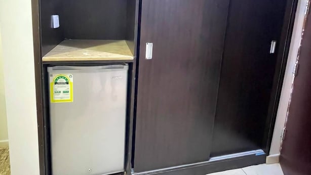 Une armoire avec une porte miroir, un petit réfrigérateur et une étagère.