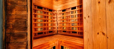 A sauna with wooden walls and benches, a ceiling light, and ventilation slats.