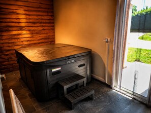 Eine Sauna mit Holzfassade, ein kleiner Podest und eine Glastür zum Garten.