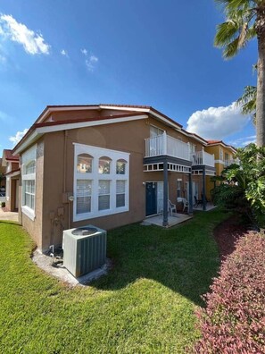 Ein zweistöckiges Wohnhaus mit Balkon, kleiner Terrasse und gepflegtem Rasen.