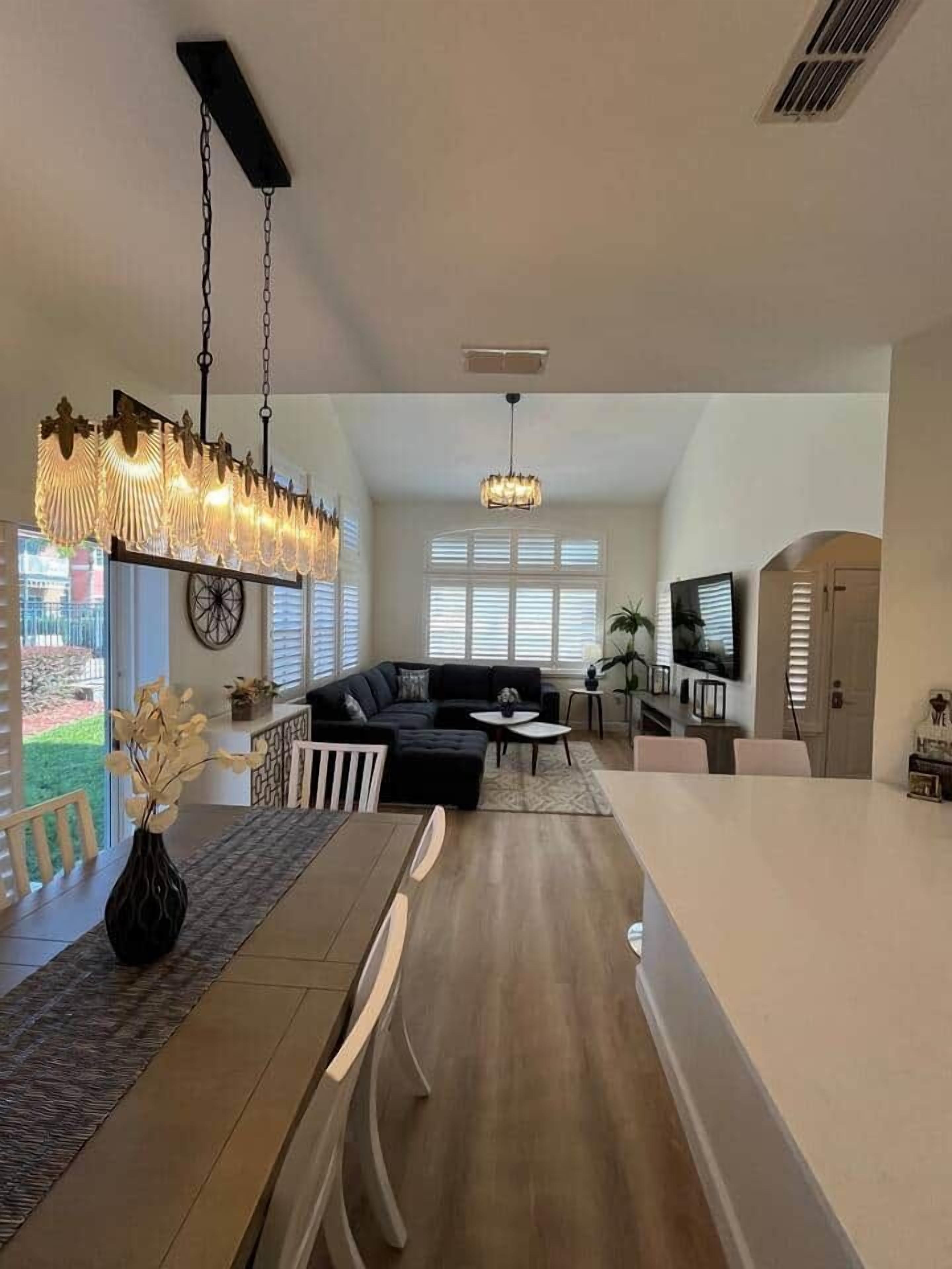 A spacious living area with a sofa, dining table, and a large chandelier.