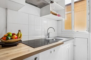Eine moderne Küche mit einem schwarzen Induktionskochfeld, einer Edelstahl-Spüle und einer Holzarbeitsplatte.