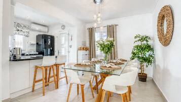 Une cuisine moderne avec une table à manger en verre, des chaises en bois et un luminaire suspendu.