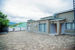 A building with a tiled patio, a satellite dish, and a green-roofed structure in the background.