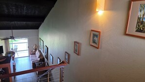 En trappa med ett räcke, en vägg med inramade tavlor och ett tak med synliga takbjälkar.