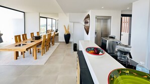 Een moderne keuken met een eethoek, een groot raam en een inbouwoven.