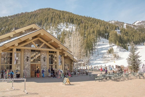 A lodge with a stone facade and large windows, surrounded by a snowy mountain landscape.