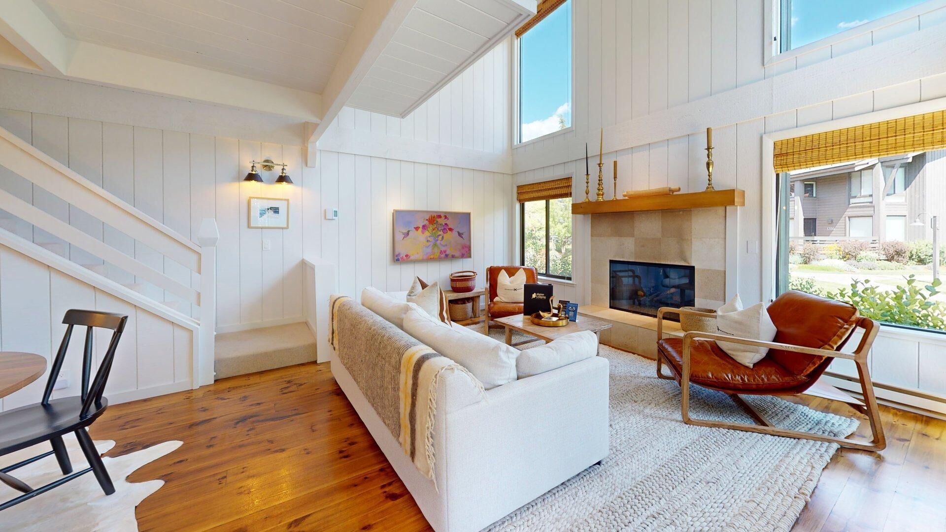 Una sala moderna con sofá, sillón, chimenea y una escalera.