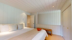 Un dormitorio con cama, banco, puerta y ventana.