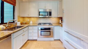 Una cocina con gabinetes blancos, un microondas Bosch, un horno Bosch, una estufa a gas y un lavamanos.
