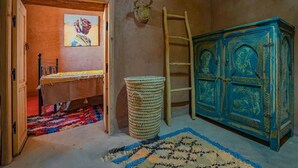 A room with a bed, a woven basket, a ladder, and a cabinet.