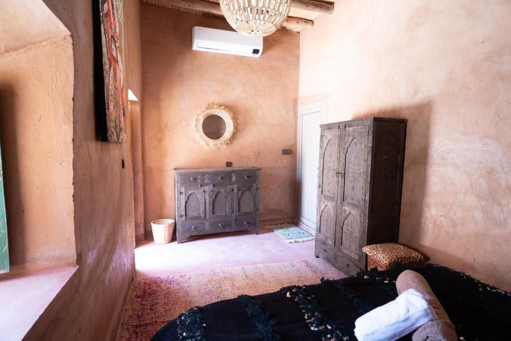 Una habitación con una cama, un armario de madera, una cesta de mimbre y un adorno circular en la pared.