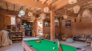 A pool table in a room with wooden beams and hanging lanterns.