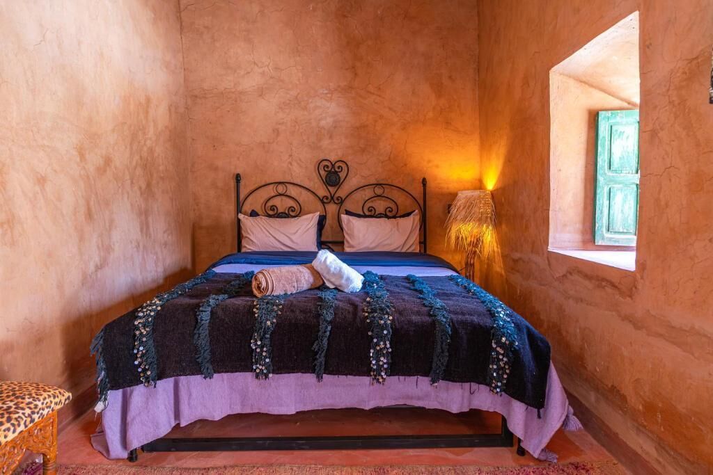 Una cama individual con cabecera, una lámpara de noche y una ventana con vistas.