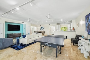 A spacious living area with a ping pong table, a flat-screen TV, and a dining area. - Mariners Club 116, VRNR Luxury Collection, Epic Amenities, Boat Slip Available (Key Largo)