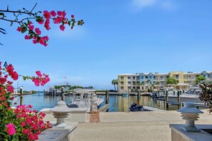 A marina with boats, a clear sky, and a multi-story building with balconies.