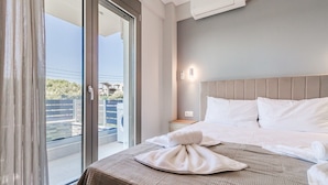 A hotel room with a bed, a nightstand, a wall-mounted air conditioner, and a sliding glass door leading to an outdoor area. - Ireon Luxury Suites 1 by RentalsPro - Nea Plagia Halkidiki (Nea Plagia)
