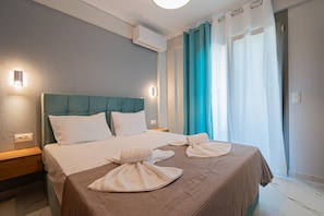 Ein Hotelzimmer mit einem Bett, einem Nachttisch, einer Wandklimaanlage und einem fenster mit Vorhängen.