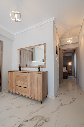 Ein modernes Badezimmer mit einem Holztischchen, einem großen Spiegel und Marmorboden.