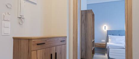 A hotel room with a wooden wardrobe, a bed, and a nightstand.
